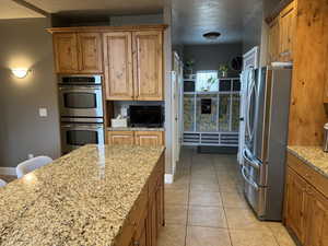 Kitchen featuring wood finish cabinets, stainless steel appliances, a breakfast bar, and light stone counters