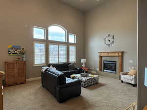 Carpeted living room with a high ceiling and a fireplace