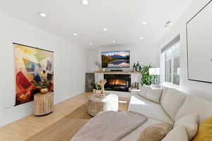 Living area featuring light wood-style flooring, recessed lighting, and a glass covered fireplace