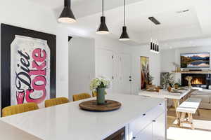 Kitchen featuring a kitchen breakfast bar, decorative light fixtures, open floor plan, a raised ceiling, and white cabinets