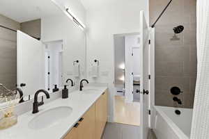 Full bathroom featuring shower / bath combination with curtain, double vanity, and light tile patterned floors