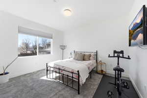 Bedroom with dark colored carpet and baseboards