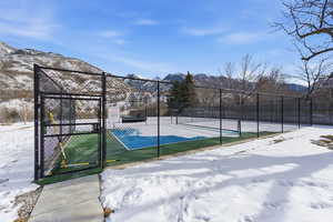 View of basketball court featuring a tennis court, a mountain view, and a gate