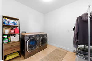 Laundry room featuring light wood finished floors and washer and clothes dryer