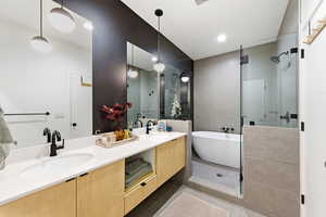 Full bath with double vanity, a freestanding bath, a shower stall, and light tile patterned floors