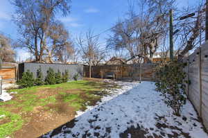 Yard layered in snow featuring a fenced backyard