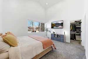Carpeted bedroom featuring a walk in closet, lofted ceiling, and recessed lighting