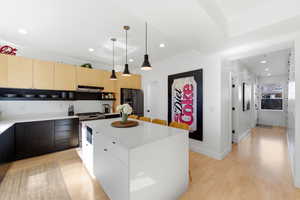 Two tone kitchen featuring dual tone cabinets, pendant lighting, a center island, light wood finished floors, and modern cabinets