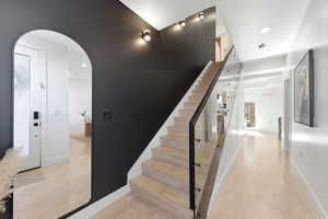 Stairs featuring arched walkways, wood finished floors, and recessed lighting