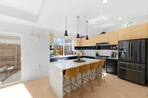 Kitchen featuring stainless steel appliances, light wood finish cabinets, light wood-style floors, modern cabinets, and light stone counters