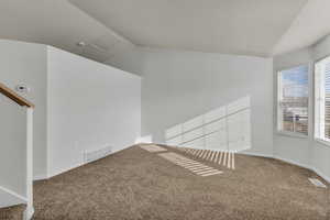 Carpeted spare room with vaulted ceiling and baseboards