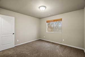 Spare room with dark colored carpet and a textured ceiling