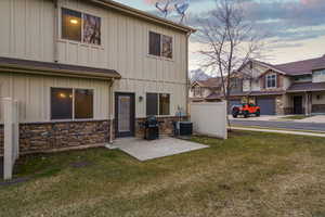 Back of property featuring board and batten siding, a yard, a patio, and stone siding