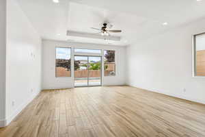Spare room with wood tiled floors, ceiling fan, recessed lighting, and a tray ceiling