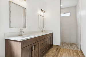 Bathroom featuring double vanity, a walk in shower, and wood finish floors