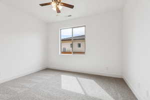 Empty room with ceiling fan and light carpet