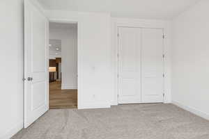 Unfurnished bedroom with light colored carpet and a closet