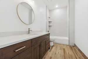 Bathroom with vanity, wood finish floors, and shower / washtub combination