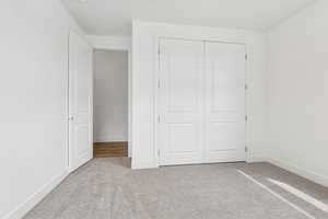 Unfurnished bedroom with light colored carpet and a closet