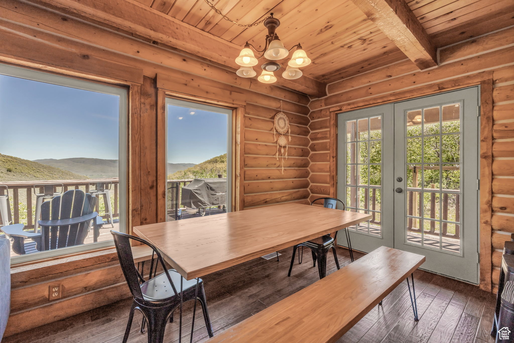 Dining room with wood-type flooring, a wood ceiling with exposed beams, french doors, suspended lighting, and log walls