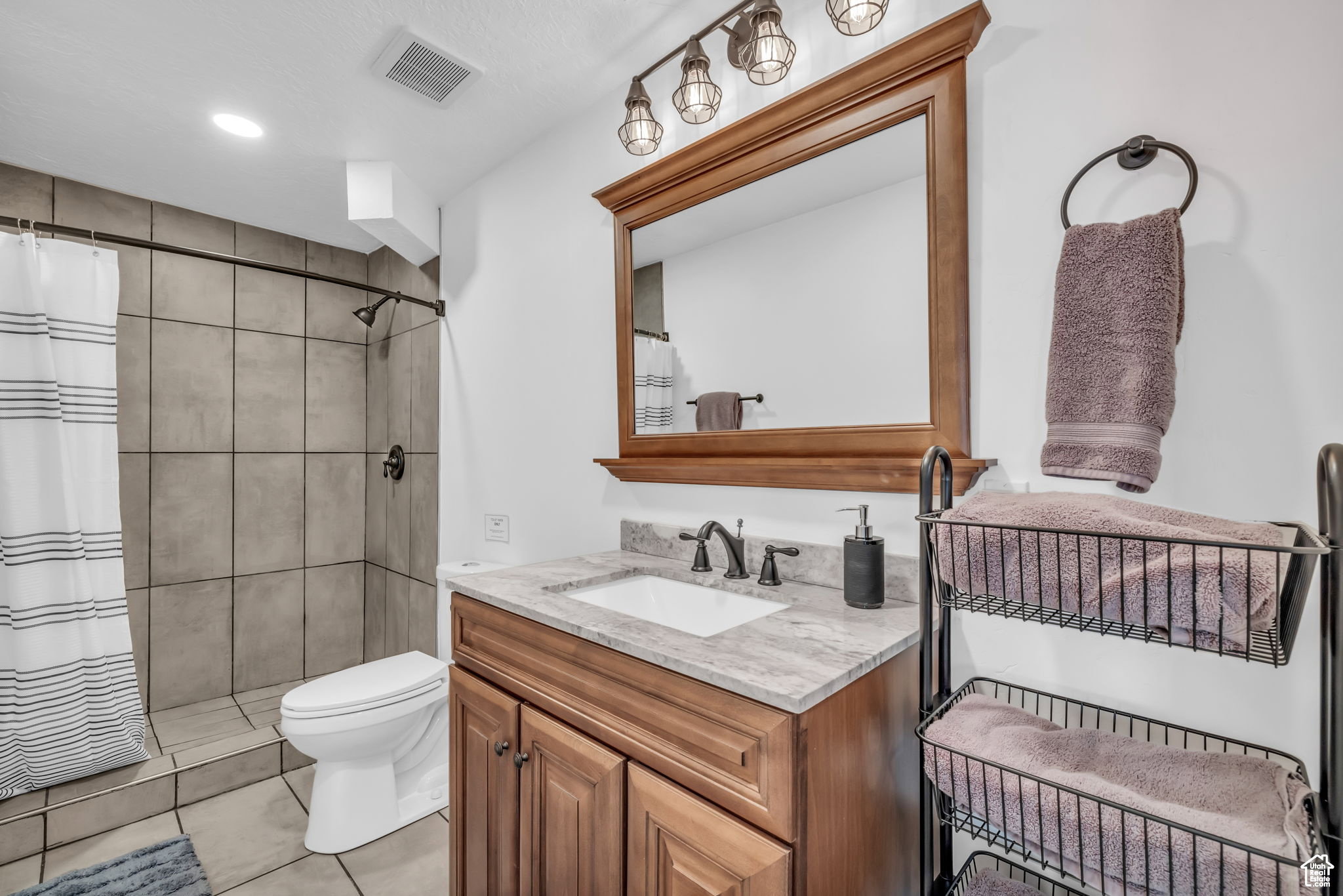 Bathroom with vanity, a tile shower, and light tile patterned floors