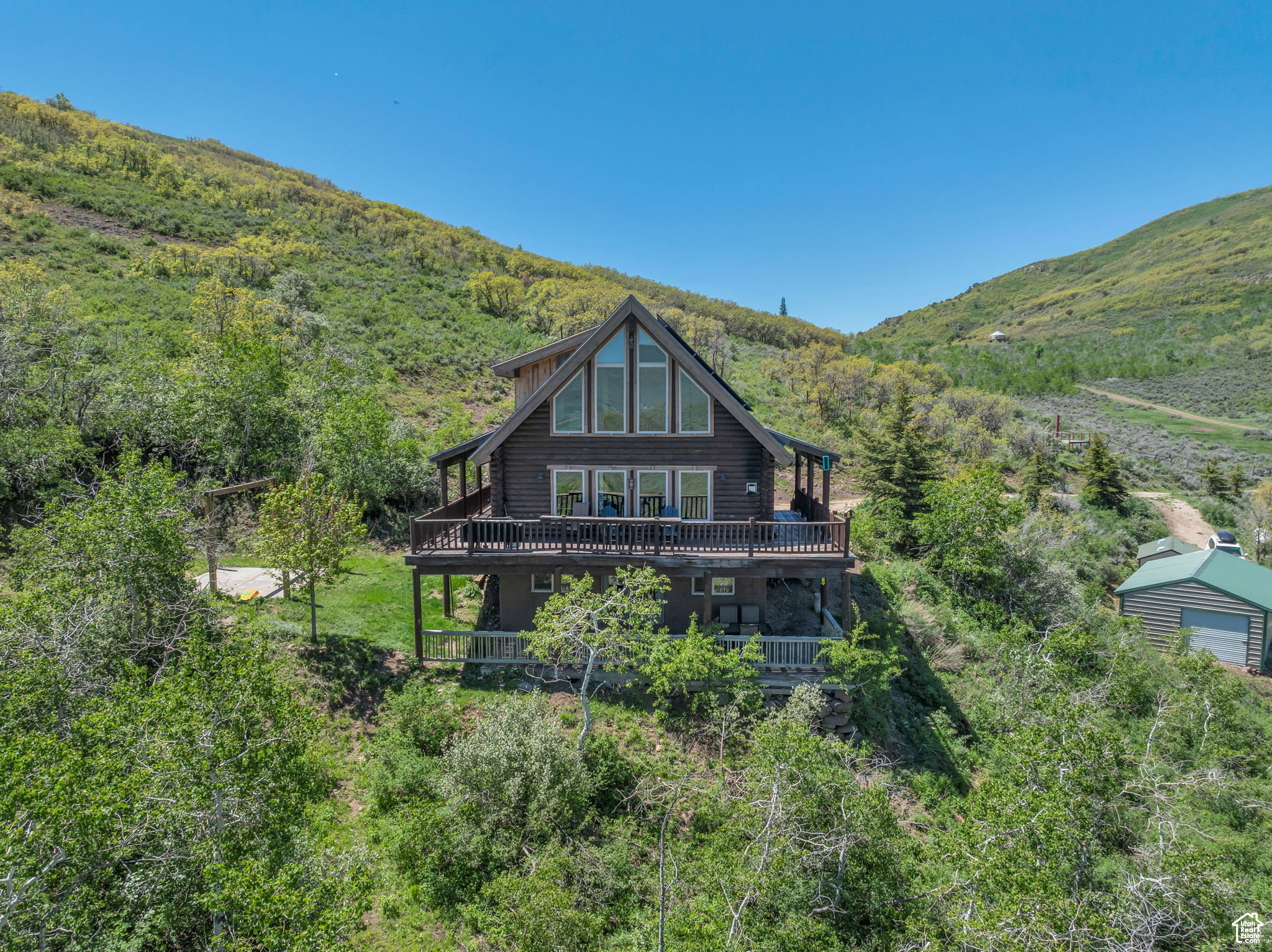 Back of property featuring log exterior, a wooded view, and a mountain view