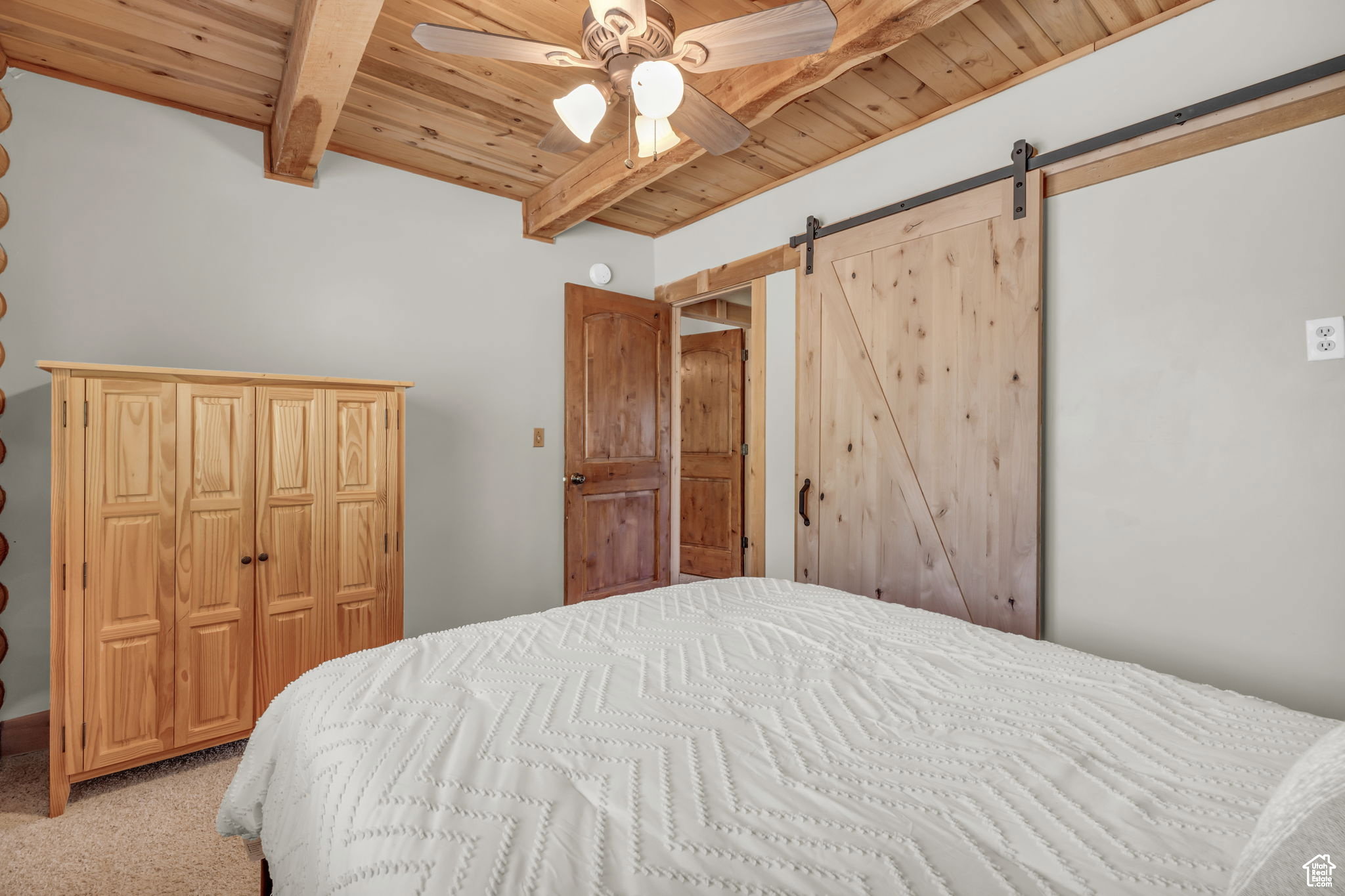 Bedroom featuring a barn door, a wooden ceiling with exposed beams, carpet floors, ceiling fan, and a closet