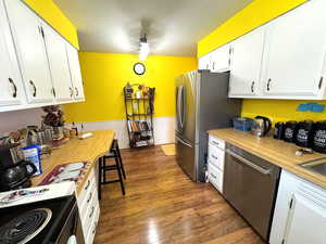 Kitchen featuring white cabinets, stainless steel appliances, light countertops, dark wood-style flooring, and a textured ceiling