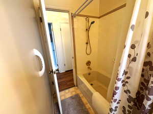 Bathroom featuring shower / bath combination with curtain and light flooring