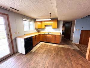 Kitchen with light countertops, light wood-type flooring, black dishwasher, and wood finish cabinetry