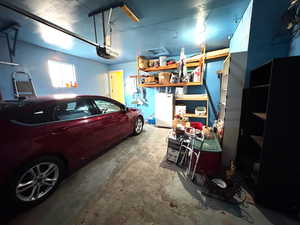 Garage featuring white refrigerator and a garage door opener