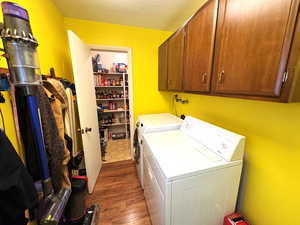 Laundry area with dark wood finished floors, washer and dryer, cabinet space, and a textured ceiling