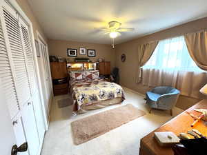 Bedroom with two closets, carpet, and ceiling fan