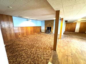 Finished basement featuring wooden walls, a wood stove, wainscoting, and light wood finished floors