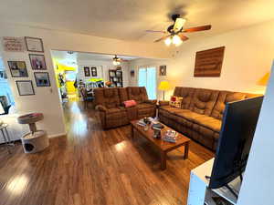 Living room with hardwood / wood-style flooring, a textured ceiling, and a ceiling fan