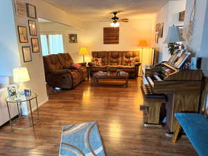 Living room with dark wood-type flooring and ceiling fan