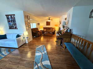Living room with dark wood-style floors, ceiling fan, and a textured ceiling