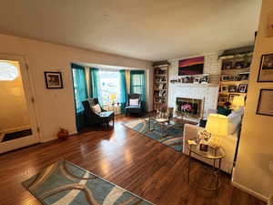 Living area with wood finished floors, a brick fireplace, built in features, and a textured ceiling