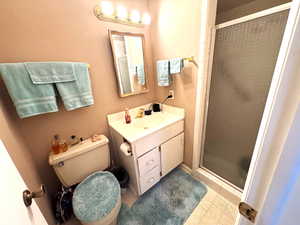 Full bathroom featuring a shower stall, vanity, and light tile patterned floors