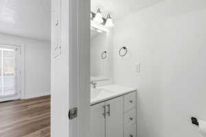 Bathroom with vanity, a textured ceiling, and light wood-style floors