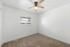 Carpeted spare room with baseboards and a ceiling fan
