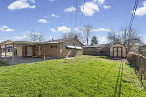 Rear view of property featuring a fenced backyard, brick siding, a patio, and a storage unit