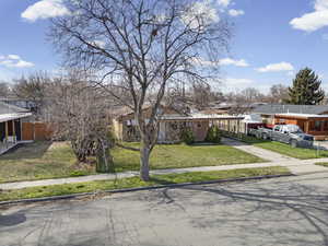 View of front of house with a front yard, an attached carport, and a residential view