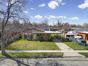 View of front facade featuring an attached carport, brick siding, driveway, and a porch