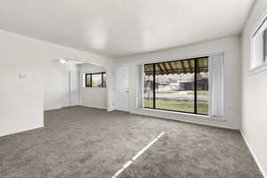Carpeted spare room with arched walkways and large window.