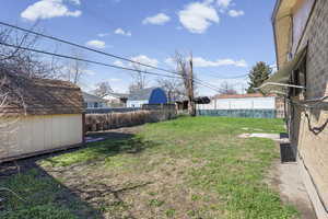 Fenced backyard featuring a storage shed
