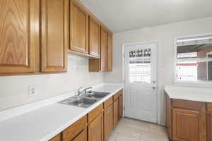 Kitchen with wood finish cabinetry, light countertops, and light tile patterned floors