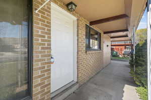 Property entrance featuring brick and covered porch