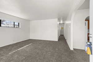 Unfurnished room featuring dark colored carpet and arched walkways