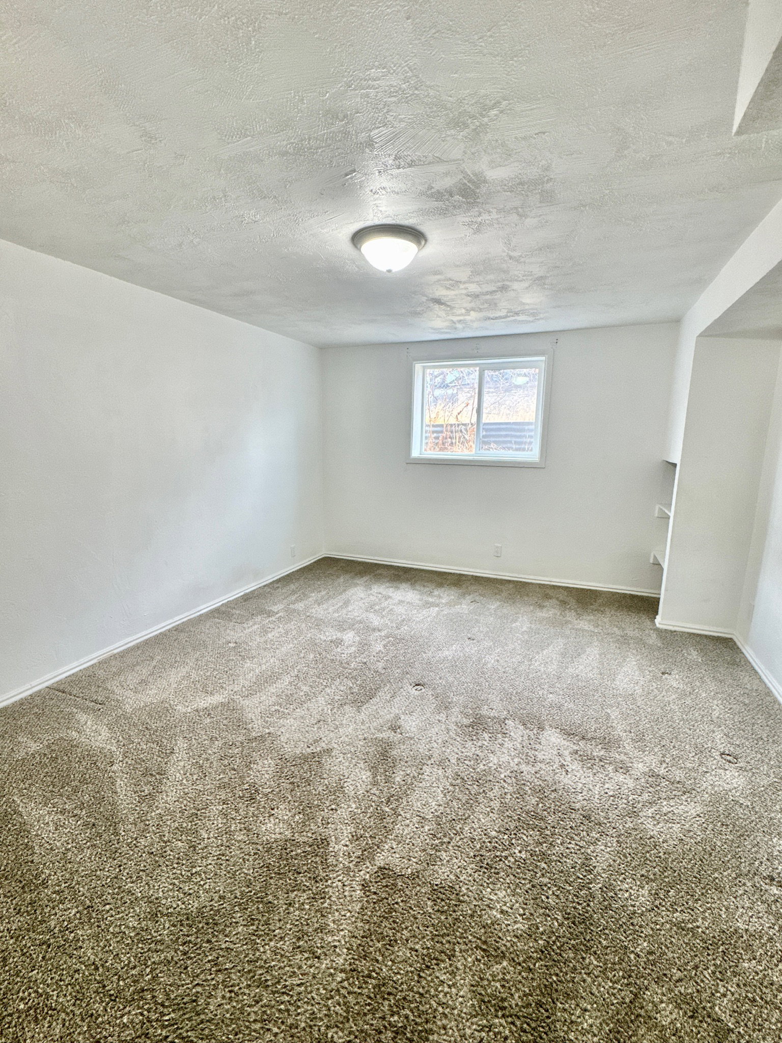Carpeted spare room featuring baseboards and a textured ceiling